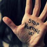 Text written on hand “stop hurting us”